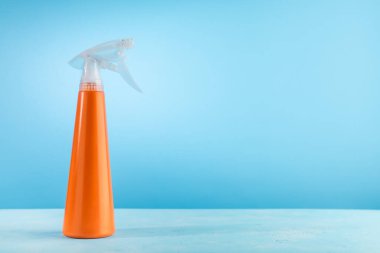 Temizleme spreyi deterjan şişesi. Bahar temizliği konsepti. Mavi arkaplanda fotokopi alanı olan plastik turuncu şişe.