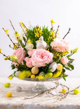 Şenlikli çiçek kompozisyonu ile Paskalya 'da hayat devam ediyor. Bahar çiçekleri, ağaç dalları, yeşil çimenler, Paskalya yumurtaları ve dekorasyonlar.