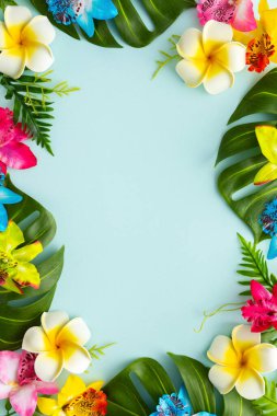 Summer background with tropical orchid flowers and green tropical palm leaves on light background. Flat lay, top view. Summer party backdrop