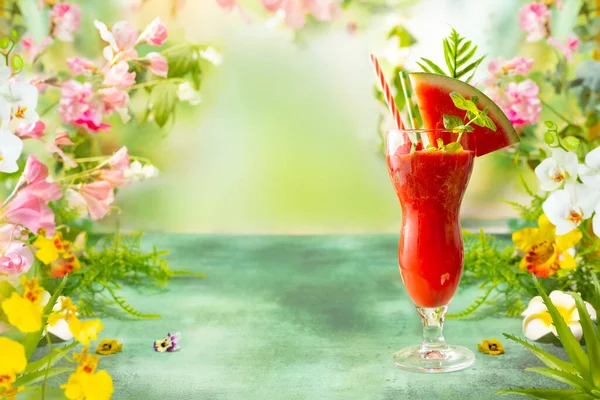 夏天的冰西瓜和草莓饮料 绿桌上的美味浆果鸡尾酒 周围环绕着热带树叶和花朵 — 图库照片