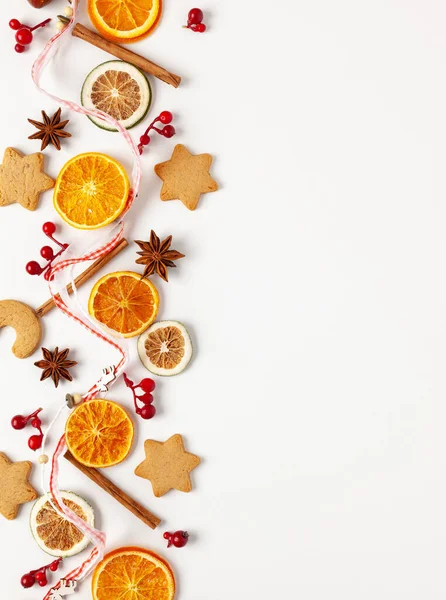 Christmas composition with cookies, dried oranges, cinnamon sticks and herbs on white background. Natural food ingredient for cooking or Christmas decor for home. Flat lay, copy space.
