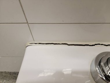 toilet in bathroom or restroom with crack in the wall or caulk