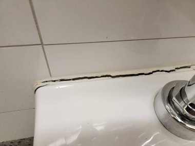 toilet in bathroom or restroom with crack in the wall or caulk