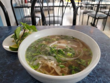 hot Vietnamese pho soup with intestine and vegetables on table