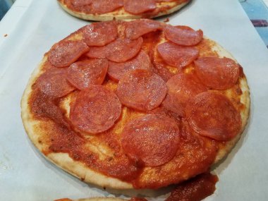 small or personal pepperoni pizza with slices of salami meat