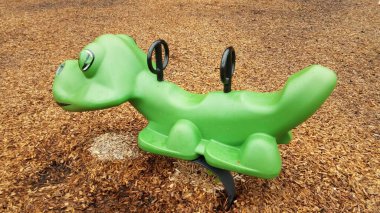 green animal ride at playground with wood chips or mulch