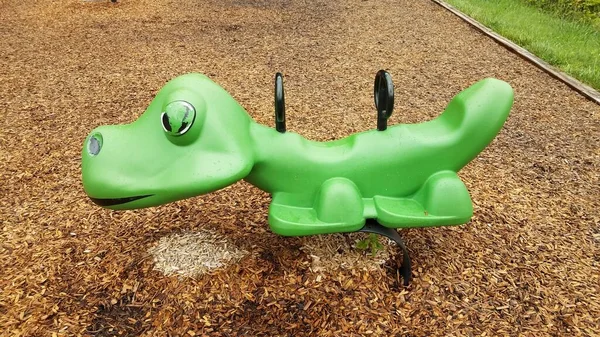 green animal ride at playground with wood chips or mulch