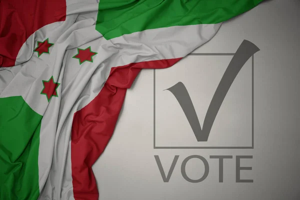 Machanie Kolorową Flagą Kraju Burundi Szarym Tle Głosowaniem Tekstowym Koncepcja — Zdjęcie stockowe