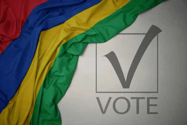 Machanie Kolorową Flagą Narodową Mauritiusa Szarym Tle Głosowaniem Tekstowym Koncepcja — Zdjęcie stockowe