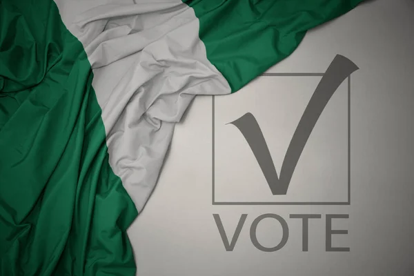 Machanie Kolorową Flagą Narodową Nigerii Szarym Tle Głosowaniem Tekstowym Koncepcja — Zdjęcie stockowe