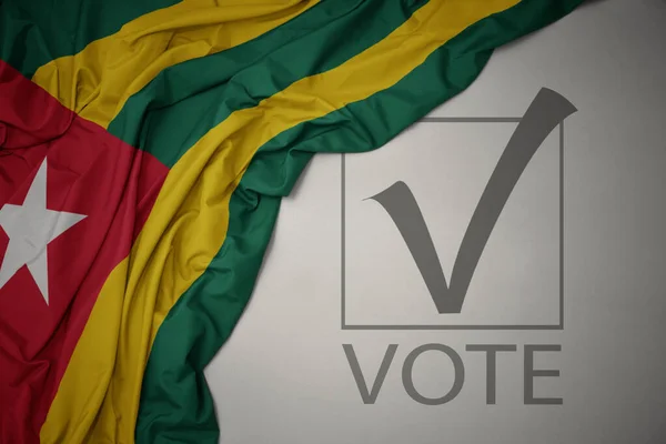 Machanie Kolorową Flagą Narodową Togo Szarym Tle Głosowaniem Tekstowym Koncepcja — Zdjęcie stockowe