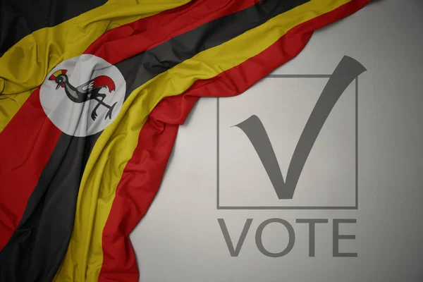 Machanie Kolorową Flagą Narodową Ugandy Szarym Tle Głosowaniem Tekstowym Koncepcja — Zdjęcie stockowe