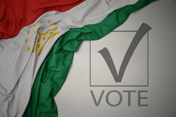 Махаючи Барвистим Національним Прапором Таджикистану Сірому Фоні Текстовим Голосуванням Концепція — стокове фото