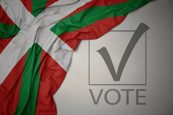 Machanie Kolorową Flagą Kraju Baskijskiego Szarym Tle Głosowaniem Tekstowym Koncepcja — Zdjęcie stockowe