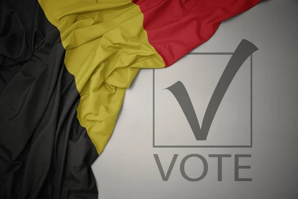 テキスト投票でベルギーのカラフルな国旗を灰色の背景に振っています 選挙の概念 3Dイラスト — ストック写真