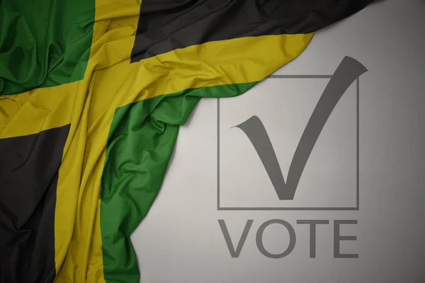 Machanie Kolorową Flagą Narodową Jamajki Szarym Tle Głosowaniem Tekstowym Koncepcja — Zdjęcie stockowe