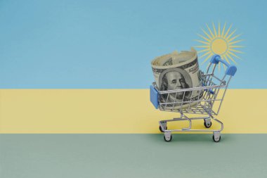 Ruanda arkaplanının ulusal bayrağında yüklü miktarda para bulunan metal alışveriş sepeti. Tüketici sepeti kavramı. 3d illüstrasyon