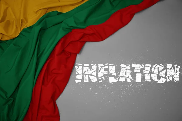 stock image waving colorful national flag of lithuania on a gray background with broken text inflation. concept. 3d illustration