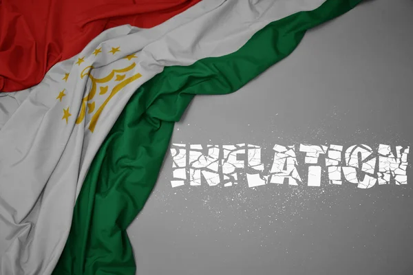 Színes Nemzeti Zászlót Lobogtatva Tajikisztán Szürke Hátterében Törött Szöveges Inflációval — Stock Fotó
