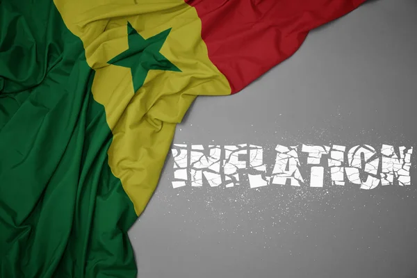 stock image waving colorful national flag of senegal on a gray background with broken text inflation. concept. 3d illustration