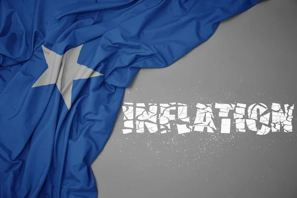 Machanie Barwną Flagą Narodową Somalii Szarym Tle Złamaną Inflacją Tekstową — Zdjęcie stockowe