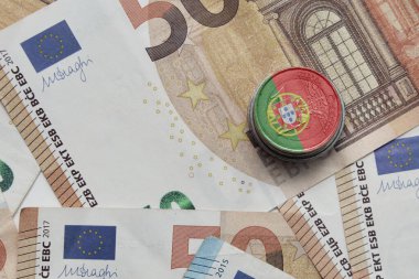 Avro para banknotlarının arka planında ulusal renkli Portekiz bayrağı bulunan euro sikkesi