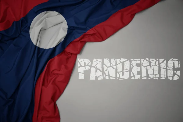Размахивая Красочным Национальным Флагом Лаоса Сером Фоне Разбитой Текстовой Пандемией — стоковое фото