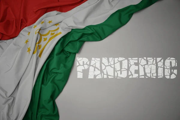 Színes Nemzeti Zászlót Lobogtatva Tajikisztán Szürke Hátterében Törött Szövegvilággal Koncepció — Stock Fotó