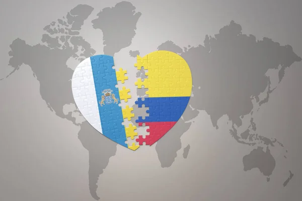コロンビアとカナリア諸島の国旗が描かれたパズルハートが世界地図の背景にあります 3Dイラスト — ストック写真