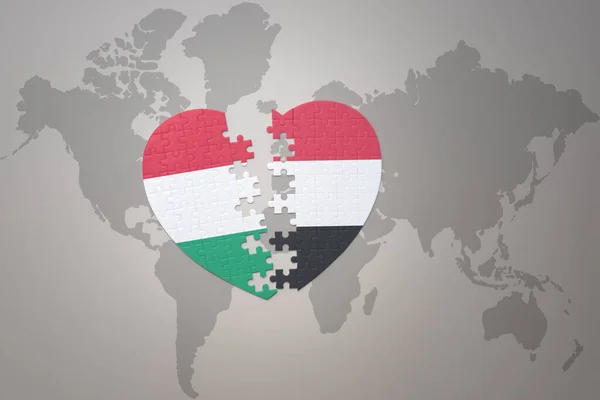 puzzle heart with the national flag of yemen and hungary on a world map background.Concept. 3D illustration