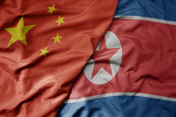 big waving national colorful flag of china and national flag of north korea . macro