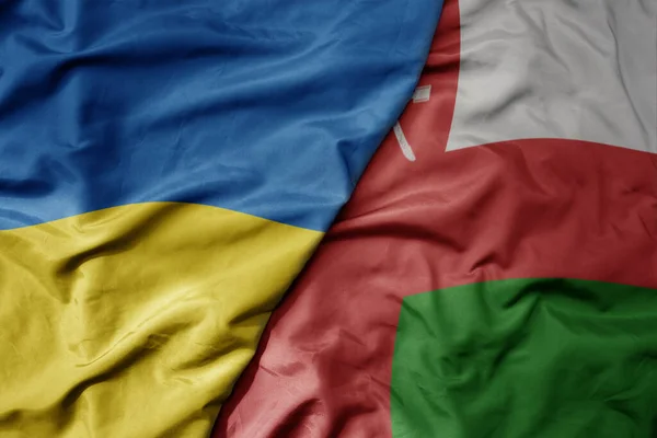 stock image big waving national colorful flag of ukraine and national flag of oman . macro