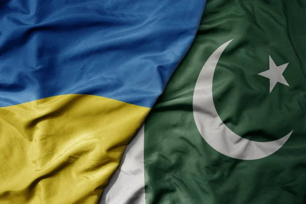 stock image big waving national colorful flag of ukraine and national flag of pakistan . macro