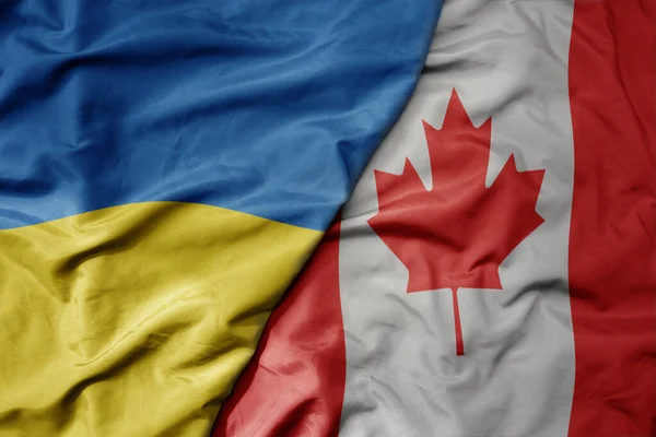 stock image big waving national colorful flag of ukraine and national flag of canada . macro