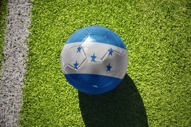 Beyaz çizginin yanındaki yeşil alanda ulusal Honduras bayrağı taşıyan futbol topu.