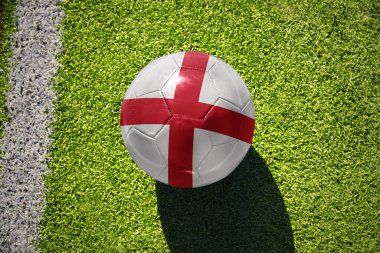 İngiltere milli bayraklı futbol topu beyaz çizginin yanındaki yeşil sahada.