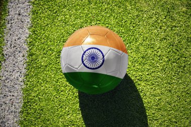 Hindistan milli bayraklı futbol topu beyaz çizginin yanındaki yeşil sahada.