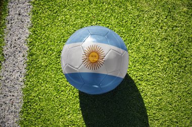 Beyaz çizginin yanındaki yeşil alanda ulusal Arjantin bayrağı taşıyan futbol topu.