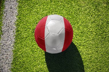 Beyaz çizginin yanındaki yeşil alanda ulusal Peru bayrağı taşıyan futbol topu.