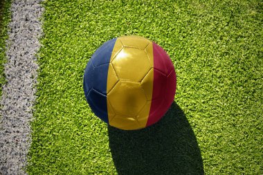 Beyaz çizginin yanındaki yeşil sahada ulusal Chad bayrağı taşıyan futbol topu.