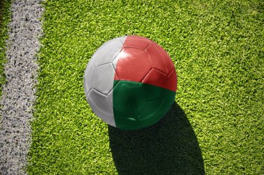 Beyaz çizginin yanındaki yeşil alanda ulusal madagaskar bayrağı taşıyan futbol topu.