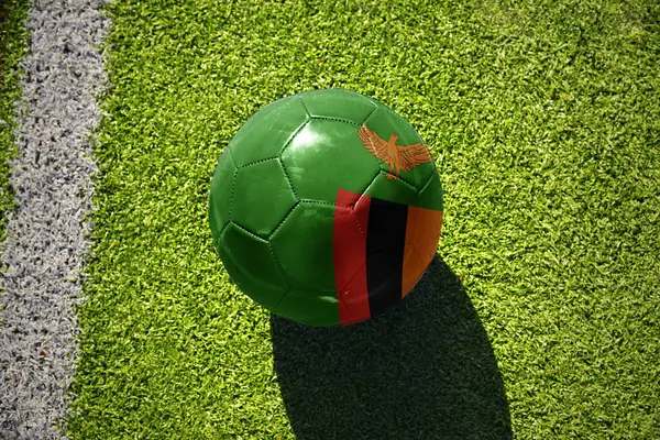 ホワイトライン近くの緑地のザンビアの国旗を持つサッカーボール ストック写真