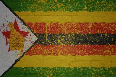 Büyük, eski tuğla bir duvarın üzerine renkli büyük bir Zimbabwe bayrağı.