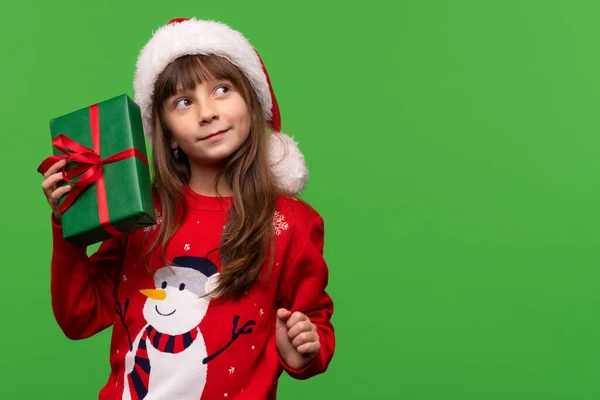 一个穿着针织毛衣 头戴圣诞帽的情绪化女孩手里拿着礼物 梦游般地抬起头 你猜怎么着 圣诞快乐 新年快乐 高质量的照片 — 图库照片