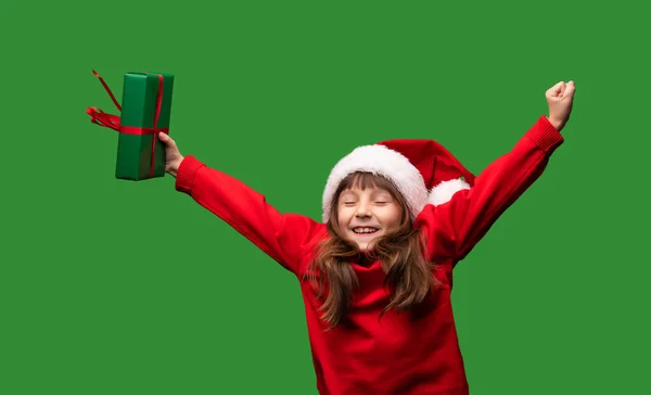一个戴着圣诞礼帽的女孩对圣诞礼物和2023年新年礼物非常满意 快乐的童年一个被绿色背景隔离的孩子的画像 高质量的照片 — 图库照片