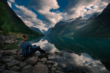 Turist Lovatnet Gölü 'ne hayranlık duyuyor. Serene Norveç fiyordu. Kristal berrak suları yüksek dağlarla çevrili.