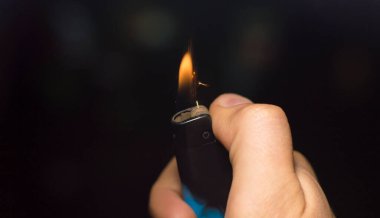 Elinde koyu bir arka planda yanan bir çakmak.