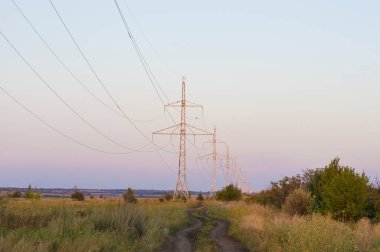 Güç hattının arka planına karşı giden toprak yol