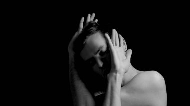 Siyah arka planda etkileyici bir duruşu olan genç bir adam.