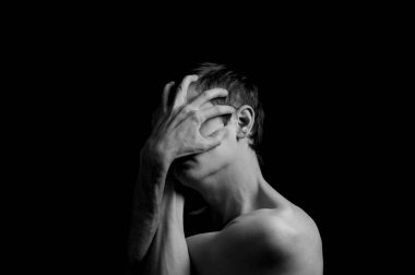 Siyah arka planda etkileyici bir duruşu olan genç bir adam.